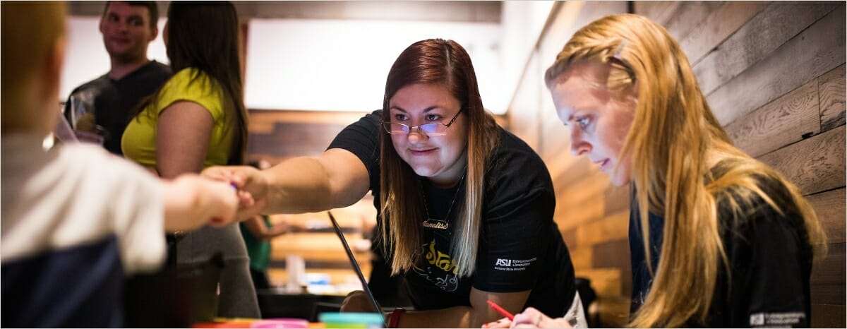 Two women assist with an Edson E+I entrepreneurship event.