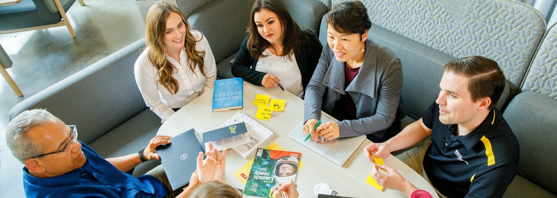 A diverse group of ASU entrepreneurs gather around a table discussing ideas.