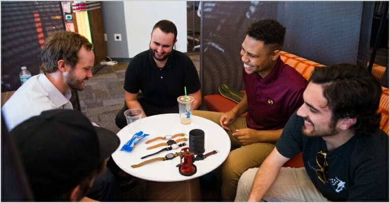 group of men sitting around table staring at watches