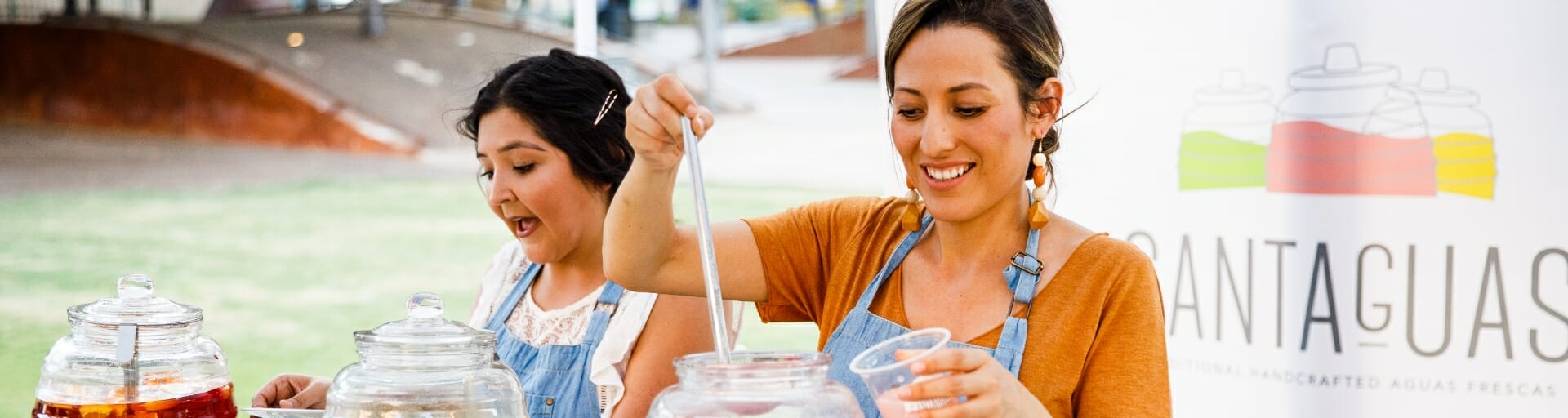 Two women work at their mobile food business serving handcrafted aguas frescas.