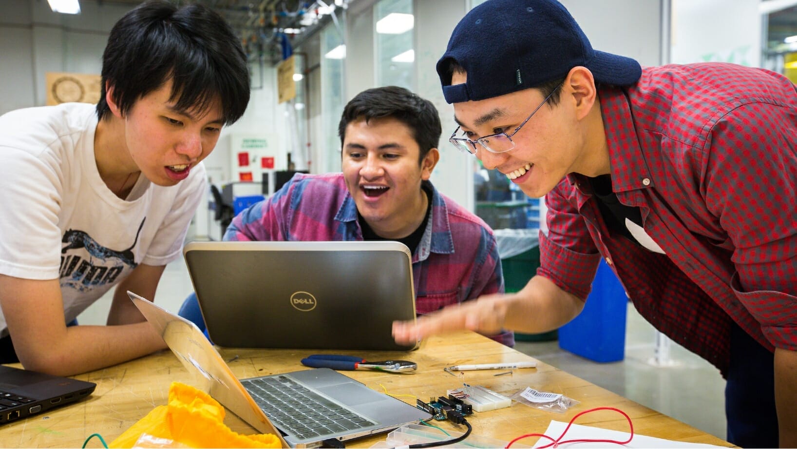 three students looking at a laptop screen